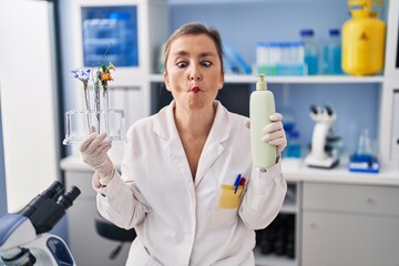 Sticker - Middle age hispanic woman working at cosmetics laboratory making fish face with mouth and squinting eyes, crazy and comical.