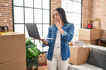 Sticker - Hispanic woman using laptop at new home covering mouth with hand, shocked and afraid for mistake. surprised expression