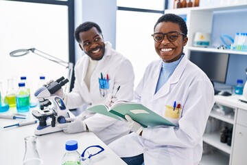 Poster - Man and woman scientists using microscope writing on notebook at laboratory