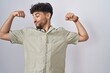© Krakenimages.com - Arab man with beard standing over white background showing arms muscles smiling proud. fitness concept.