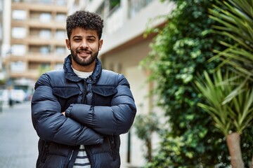 Sticker - Young arab man smiling with crossed arms outdoor at the town