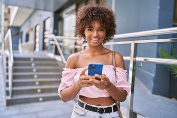 Sticker - Young african american girl smiling happy using smartphone at the city.