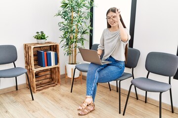 Sticker - Young asian nurse woman sitting at waiting room using laptop smiling happy doing ok sign with hand on eye looking through fingers