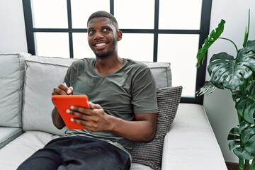 Wall Mural - Young african american man smiling confident using touchpad at home