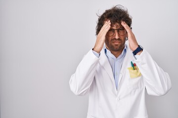 Poster - Hispanic young man wearing doctor uniform with hand on head for pain in head because stress. suffering migraine.