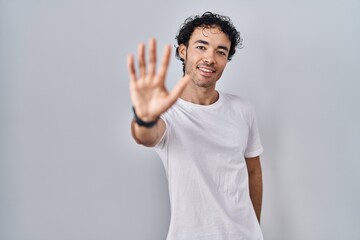 Wall Mural - Hispanic man standing over isolated background showing and pointing up with fingers number five while smiling confident and happy.