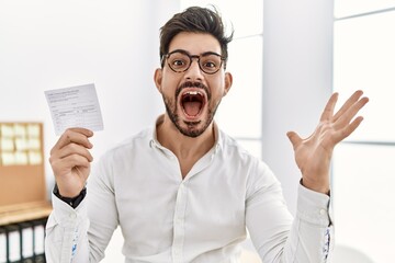 Poster - Young man with beard holding covid record card celebrating victory with happy smile and winner expression with raised hands