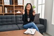 © Krakenimages.com - Young asian woman at consultation office gesturing finger crossed smiling with hope and eyes closed. luck and superstitious concept.