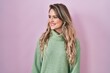 © Krakenimages.com - Young caucasian woman standing over pink background looking away to side with smile on face, natural expression. laughing confident.