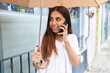 © Krakenimages.com - Young beautiful arab woman talking on smartphone holding umbrella at street