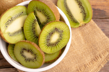 Wall Mural - fresh green kiwis slice in the white bowl on the old wooden table