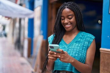 Wall Mural - African american woman smiling confident using smartphone at street