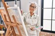© Krakenimages.com - Middle age grey-haired woman artist smiling confident drawing at art studio