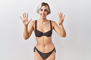 Sticker - Young beautiful woman wearing swimsuit over isolated background showing and pointing up with fingers number nine while smiling confident and happy.