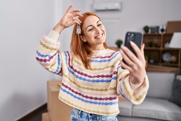 Wall Mural - Young caucasian woman having video call holding key at new home