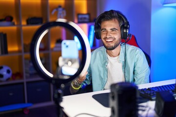 Young hispanic man with tattoos recording tutorial with smartphone celebrating surprised and amazed for success with arms raised and eyes closed