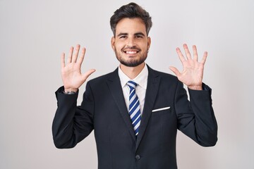 Sticker - Young hispanic man with tattoos wearing business suit and tie showing and pointing up with fingers number ten while smiling confident and happy.