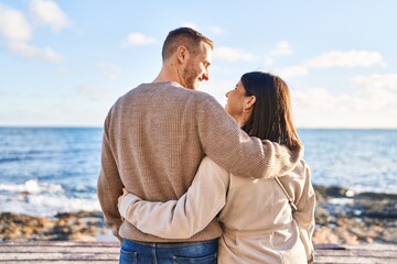 Man and woman couple hugging each other standing on back view at seaside