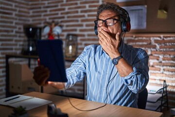 Poster - Middle age hispanic man using touchpad sitting on the table at night bored yawning tired covering mouth with hand. restless and sleepiness.