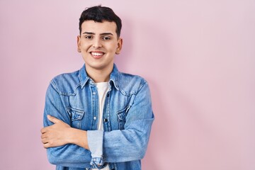 Sticker - Non binary person standing over pink background happy face smiling with crossed arms looking at the camera. positive person.