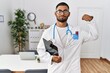 © Krakenimages.com - Young indian man wearing doctor uniform and stethoscope strong person showing arm muscle, confident and proud of power