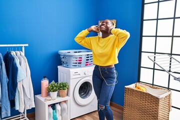 Poster - African american woman liatening to music waiting for washing machine at laundry room