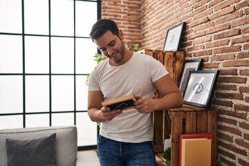 Wall Mural - Young hispanic man looking photo standing at home