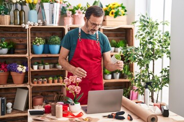 Sticker - Middle age man florist using laptop holding plant at florist