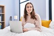 © Krakenimages.com - Young beautiful hispanic woman using laptop sitting on bed at bedroom