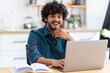 © kucherav - Portrait of a successful happy Asian entrepreneur or freelancer, sitting at the table in the home office, working, looking at the camera and smiles friendly. Remote online work outside the office