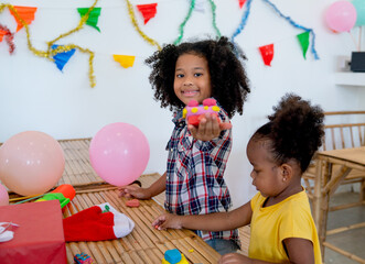 African American little girl show the result from molding the plasticine or play dough and she look happy to create from her idea in school room.