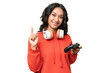 © luismolinero - Young Argentinian woman playing with a video game controller over isolated background showing and lifting a finger in sign of the best