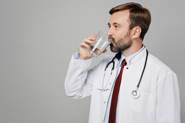 Wall Mural - Side profile view male doctor fun happy man wears white medical gown suit work in hospital drink water hold glass isolated on plain grey color background studio portrait. Healthcare medicine concept.