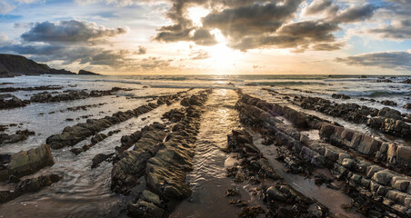 Wall Mural - Beautiful sunset landscape image of Welcome Mouth Beach in Devon England with beautiful rock formations