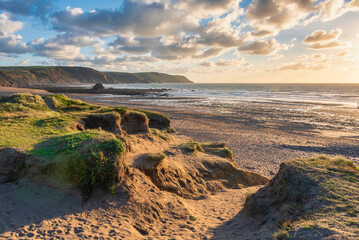 Wall Mural - Stunning Summer sunset landscape image of Widemouth Bay in Devon England with golden hour light on beach
