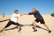 © KAMPUS - Side view of healthy aged couple having fun of sport outdoors. Smiling man and woman standing on sand holding their stretched hands exercising in flexibility. Aged peoples active life, health concept