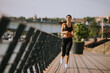 © BGStock72 - Active young beautiful woman running on the promenade along the riverside