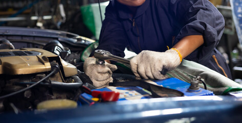 African young female car mechanic checking and fixing car engine at service car garage. Black woman mechanic working in car service and maintenance workshop.