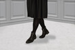 Close up of female legs in black Chelsea boots, black skirt and black tights. Autumn or spring fashion collection.