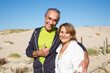 © KAMPUS - Portrait of sporty aged couple on blue sky and sand background. Happy man and woman resting after active training hugging and looking at camera. Active lifestyle and sport for aged people concept