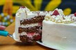 Closeup of a hand taking a piece of a delicious cake with strawberry, chocolate and cream