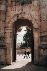 Poster - Vertical shot of an archway in an old building with people walking in the background