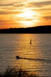 Sailboat and motorboat on the water where Mediterranean sunset is reflected