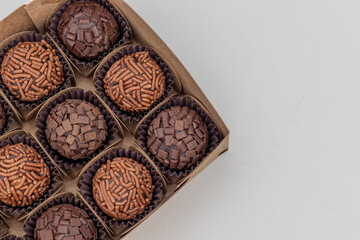 Box with several brigadeiros lined up on white background. Brazilian traditional sweet.