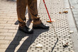 © thomsond - Close-up of a blind man with a walking stick. Detects tactile tiles for self-orientation while moving through the streets of the city