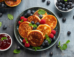 Wall Mural - Cottage cheese pancakes served with blueberries, raspberries, strawberry jam and mint leaves, healthy vegetarian protein breakfast