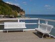 View of white benches on beach surrounded by water