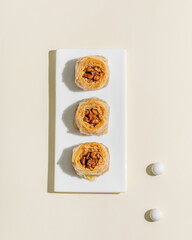 Sticker - Classic turkish baklava with walnuts  on white plate top view on cream background