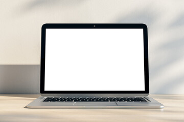 Closeup of modern laptop with blank white screen and place for your logo or text on light wooden table and sunlit wall background. 3D rendering, mock up