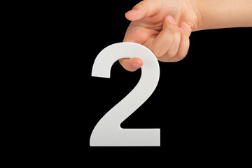Aufkleber - number two in hand isolated on black background. Number two white in a child's hand on a black background. For inserting into a project or design.